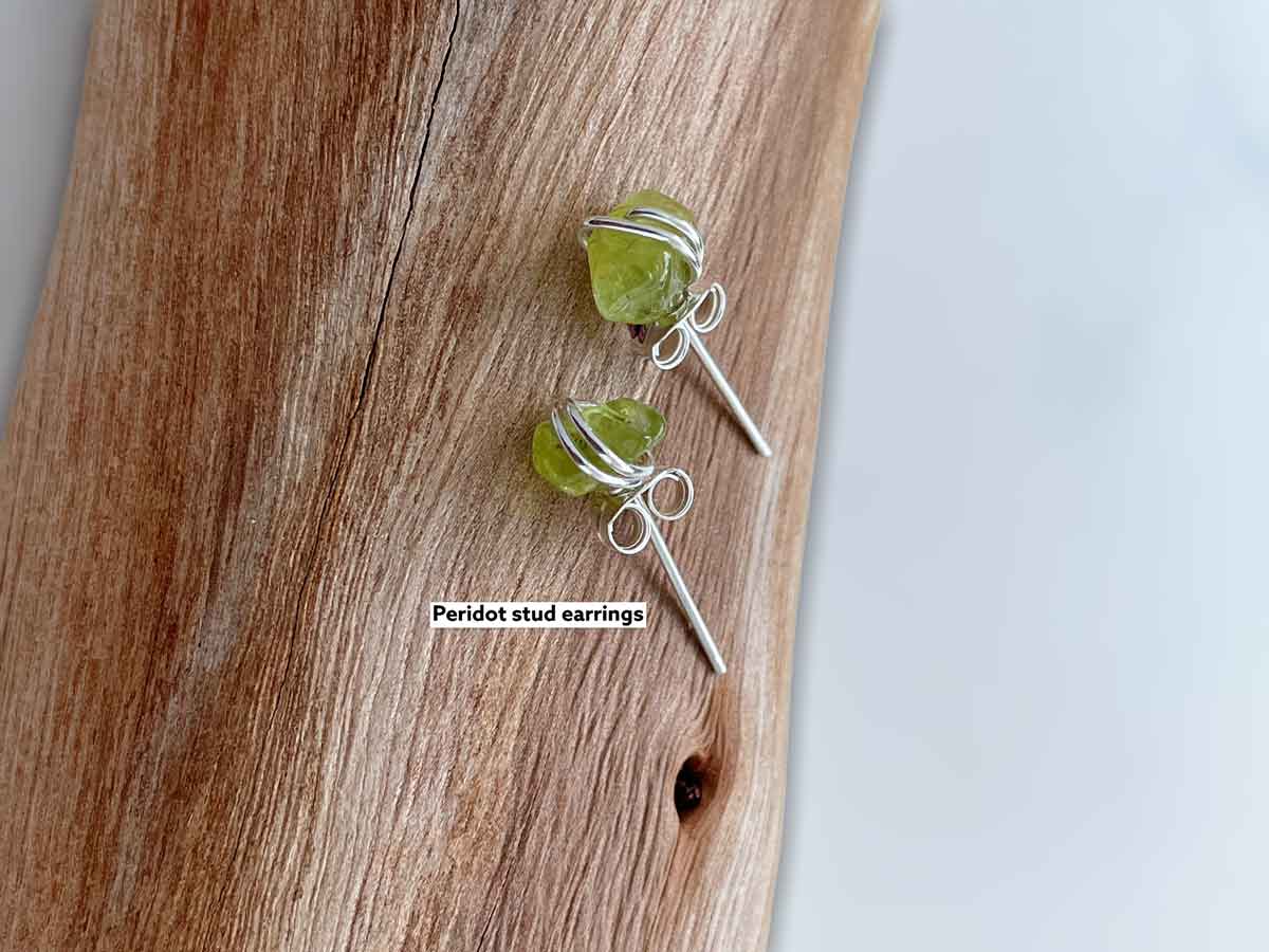 peridot gemstone earrings resting on a log