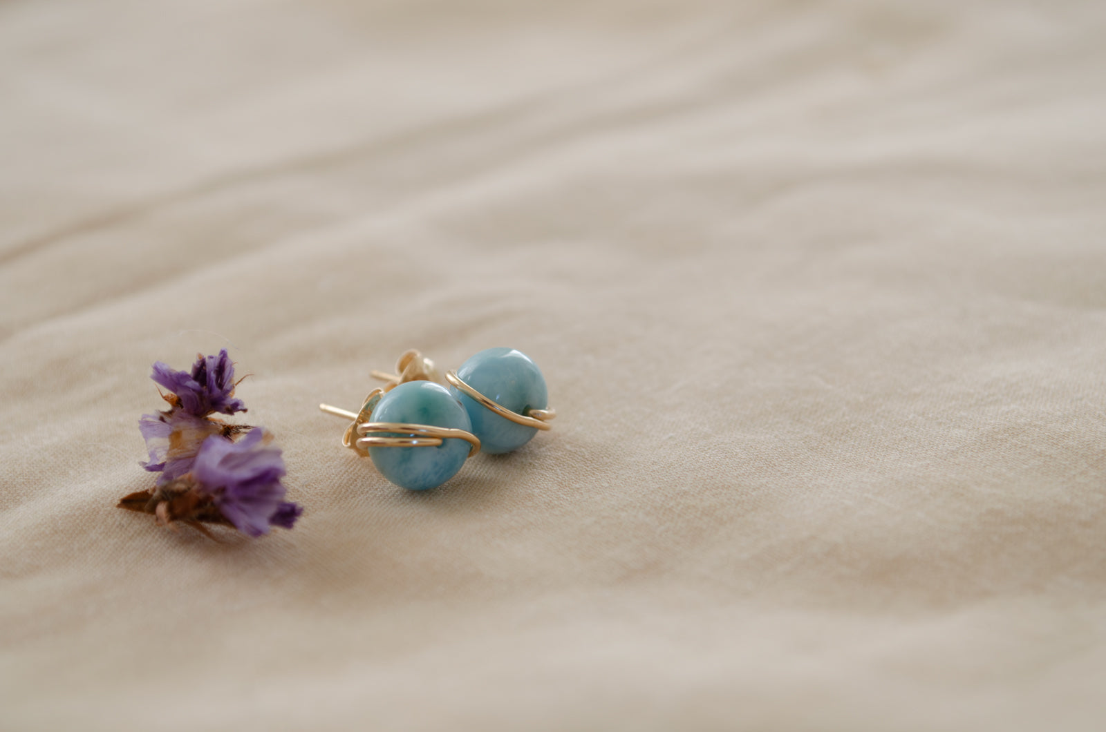 Gold larimar studs on a beach 
