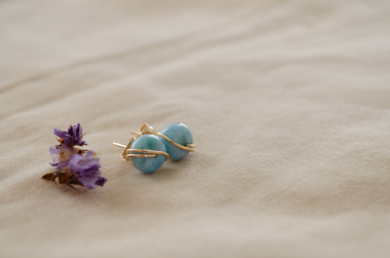 Gold larimar studs on a beach 
