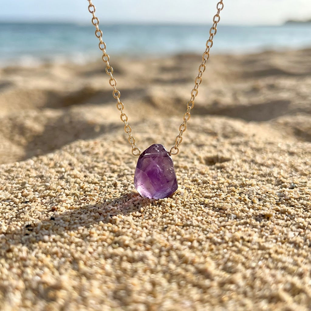 Necklace with a purple pendant on a sandy beach