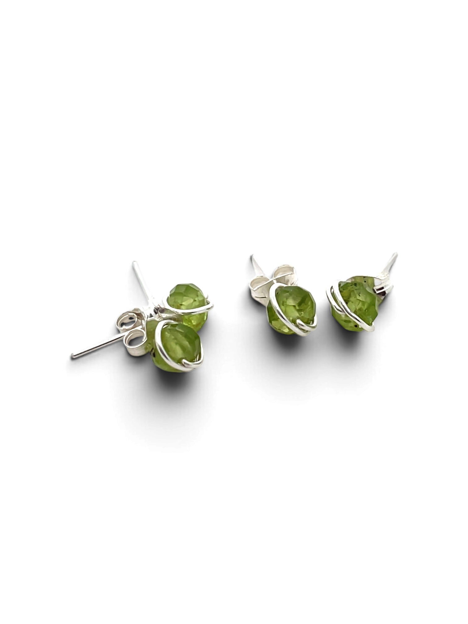 A pair of silver stud earrings featuring small, faceted green gemstones wrapped in delicate silver wire, shown on a clean white background.