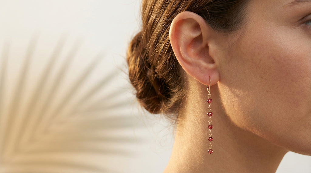 Close-up of a woman wearing red beaded earrings with a neutral background