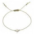 Beige bracelet with a small round bead featuring the letter 'G' on a white background