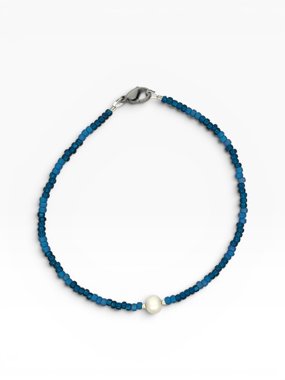 Blue beaded anklet with a white pearl on a white background