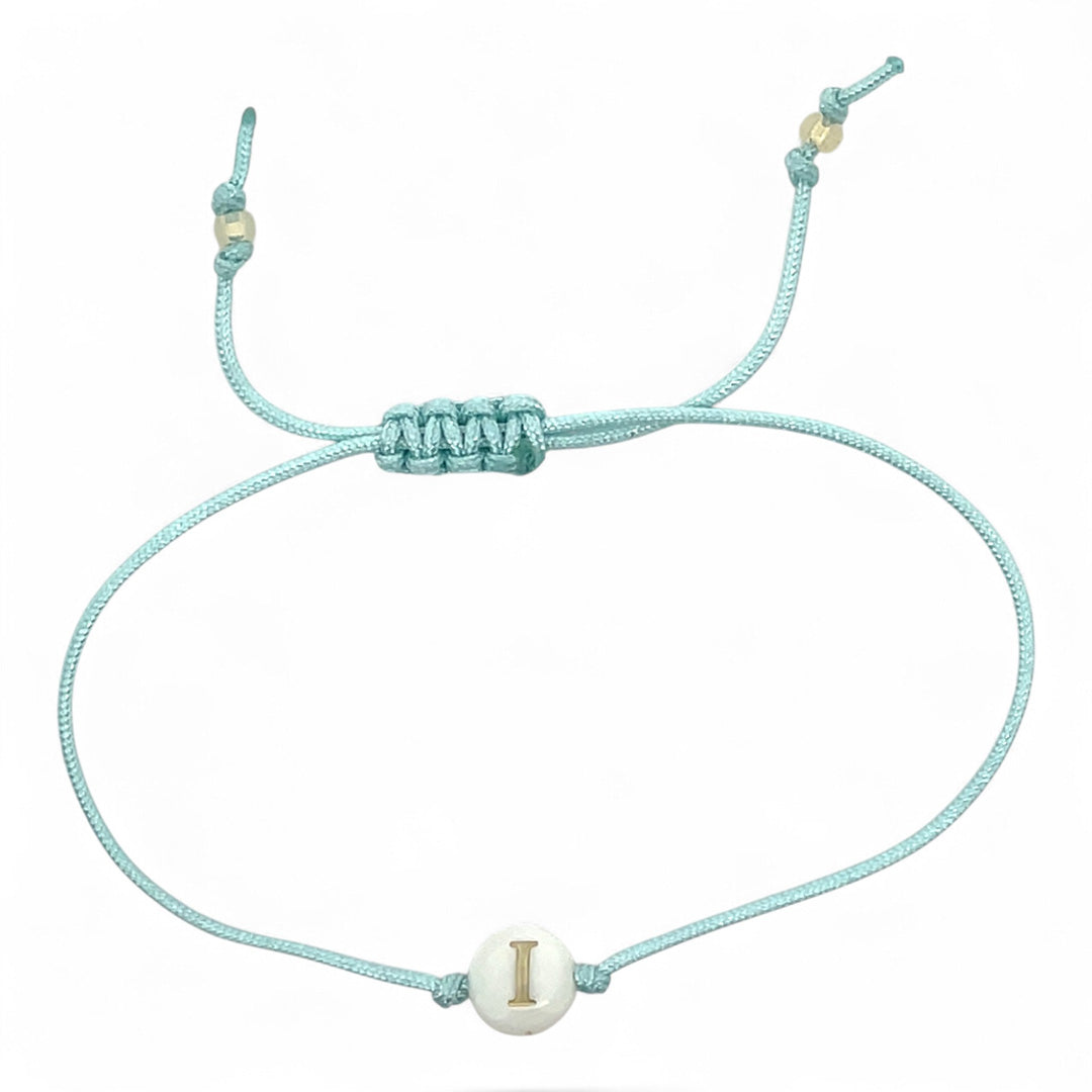 Light blue bracelet with a white bead featuring a gold letter 'I' on a white background