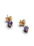 A pair of gold stud earrings with a small round purple gemstone, shown on a clean white background.