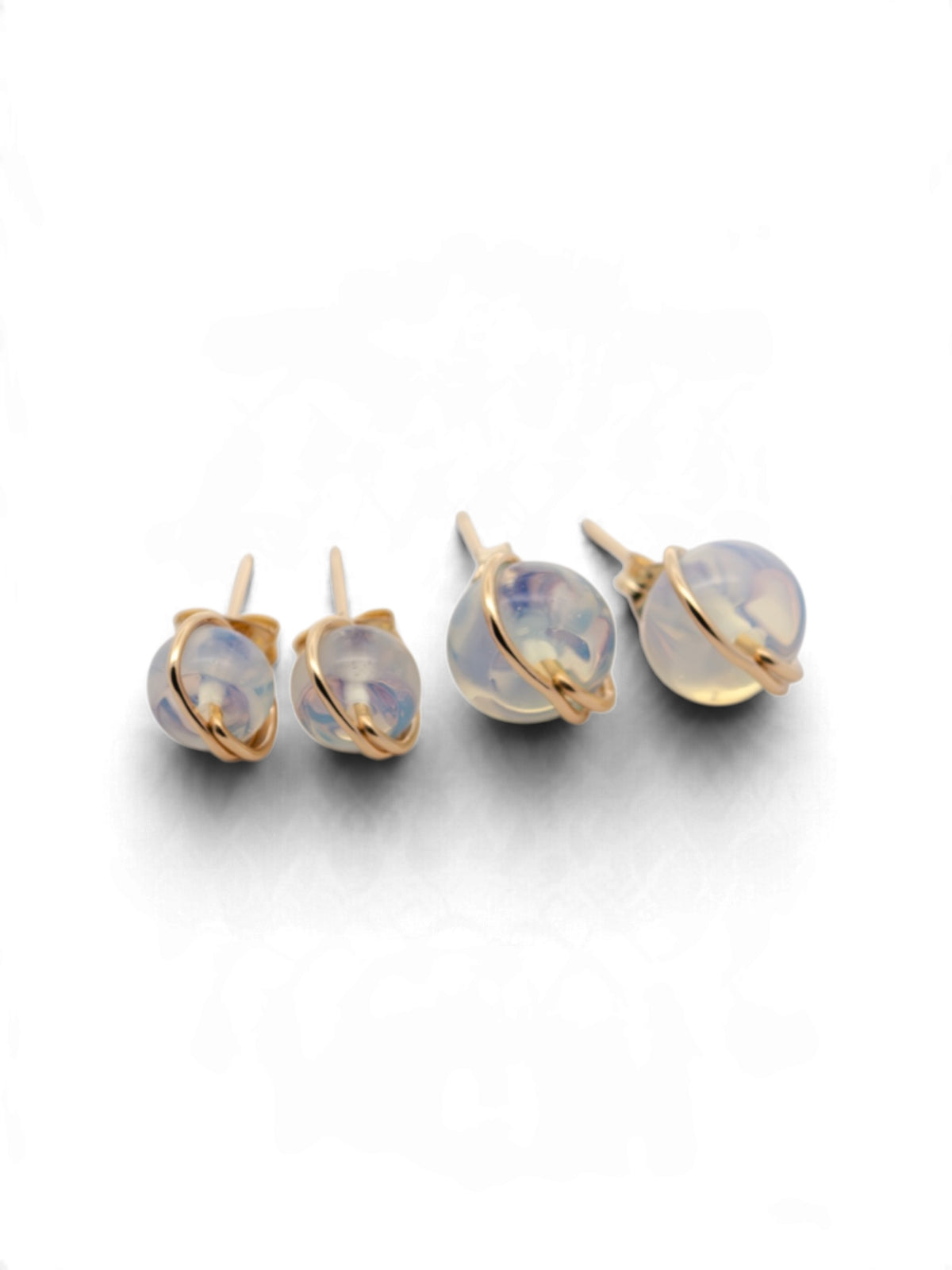 A set of gold-toned stud earrings with round iridescent opal-like cabochons, shown on a clean white background.