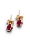 A pair of gold stud earrings with oval-cut deep pinkish-red gemstones, shown on a clean white background with soft shadows.