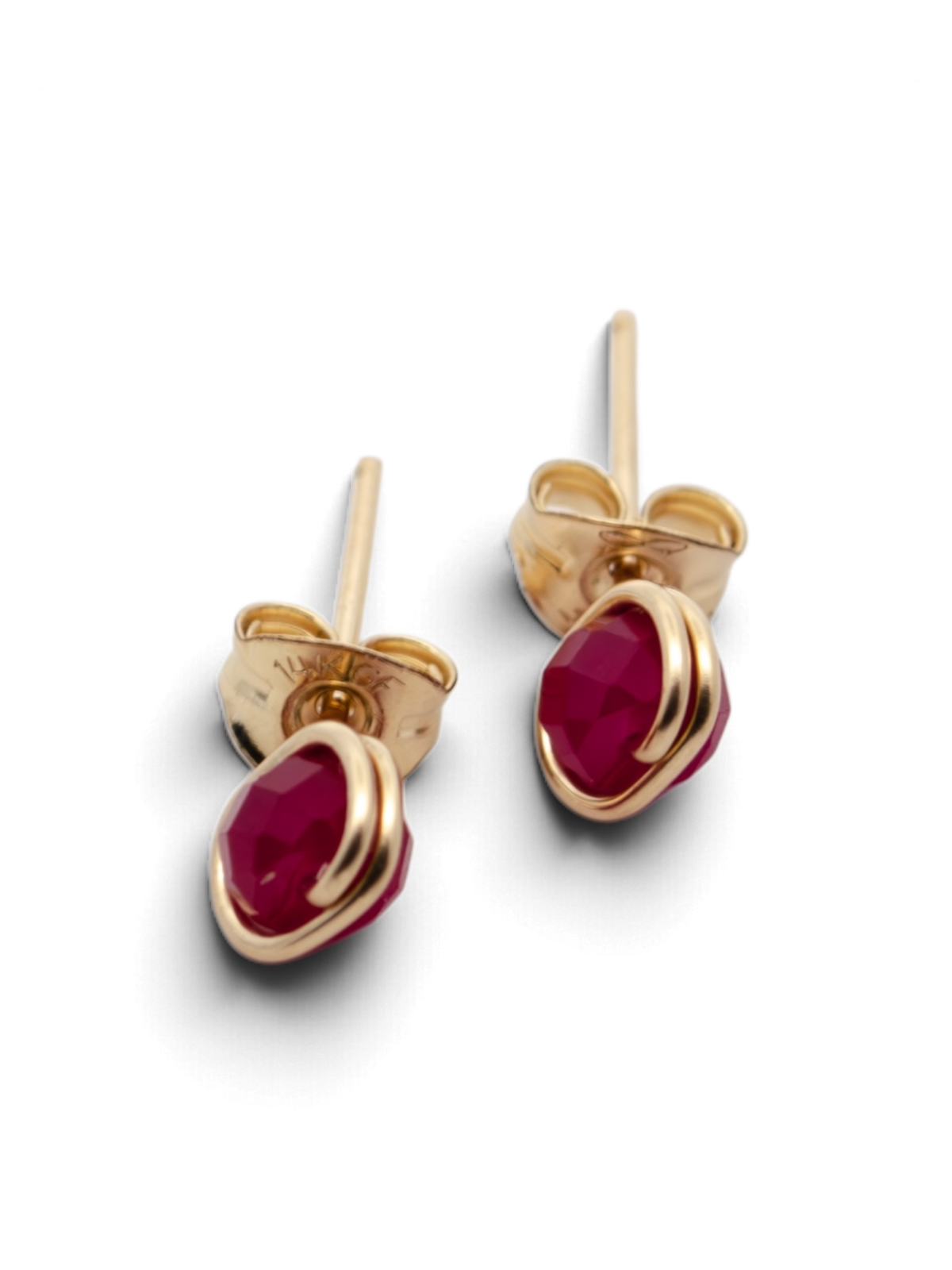 A pair of gold stud earrings with oval-cut deep pinkish-red gemstones, shown on a clean white background with soft shadows.
