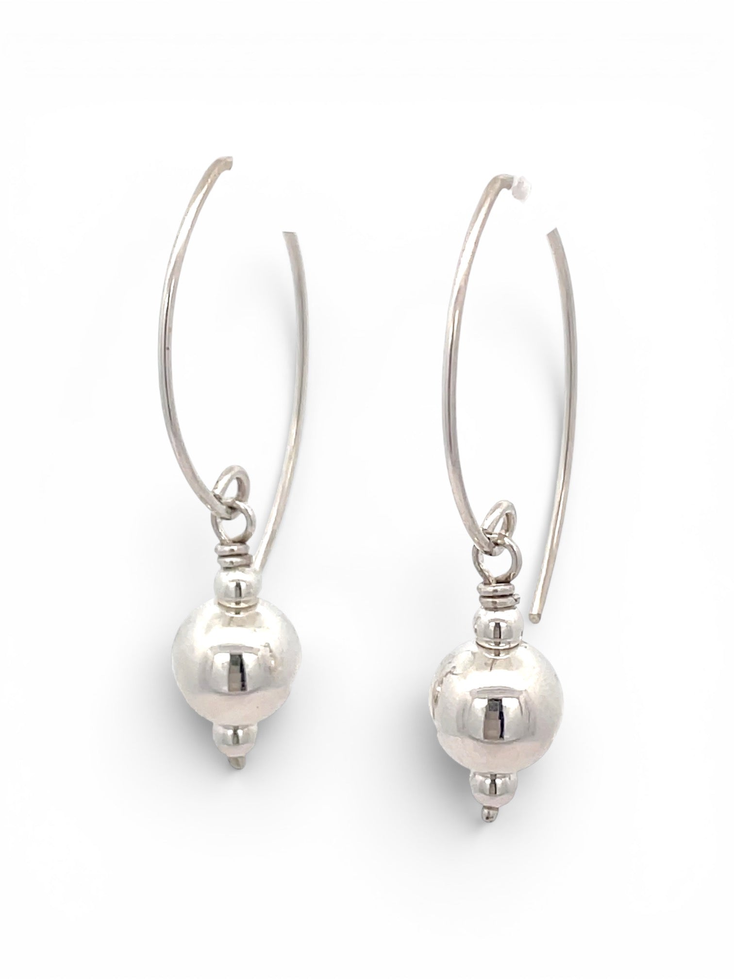 A pair of silver drop hoop earrings with a polished spherical bead hanging from a thin curved wire, shown on a plain white background.