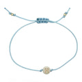 Light blue cord bracelet with a gold 'H' charm on a white background