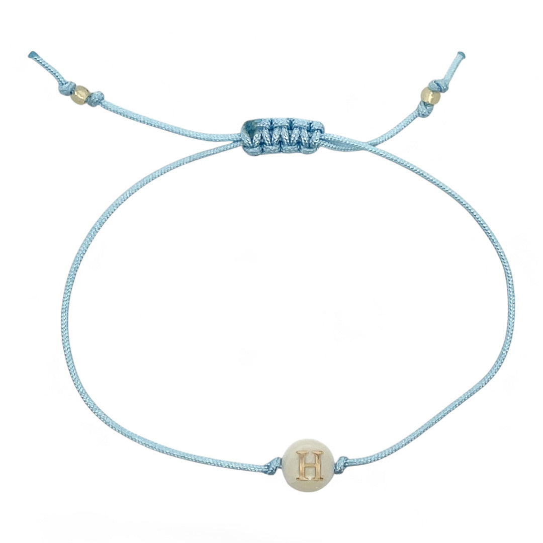 Light blue cord bracelet with a gold 'H' charm on a white background