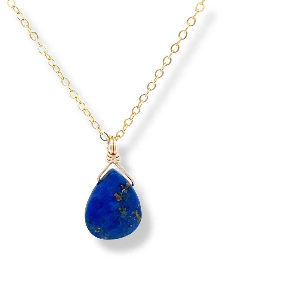 Gold lapis lazuli necklace with a blue teardrop pendant on a white background