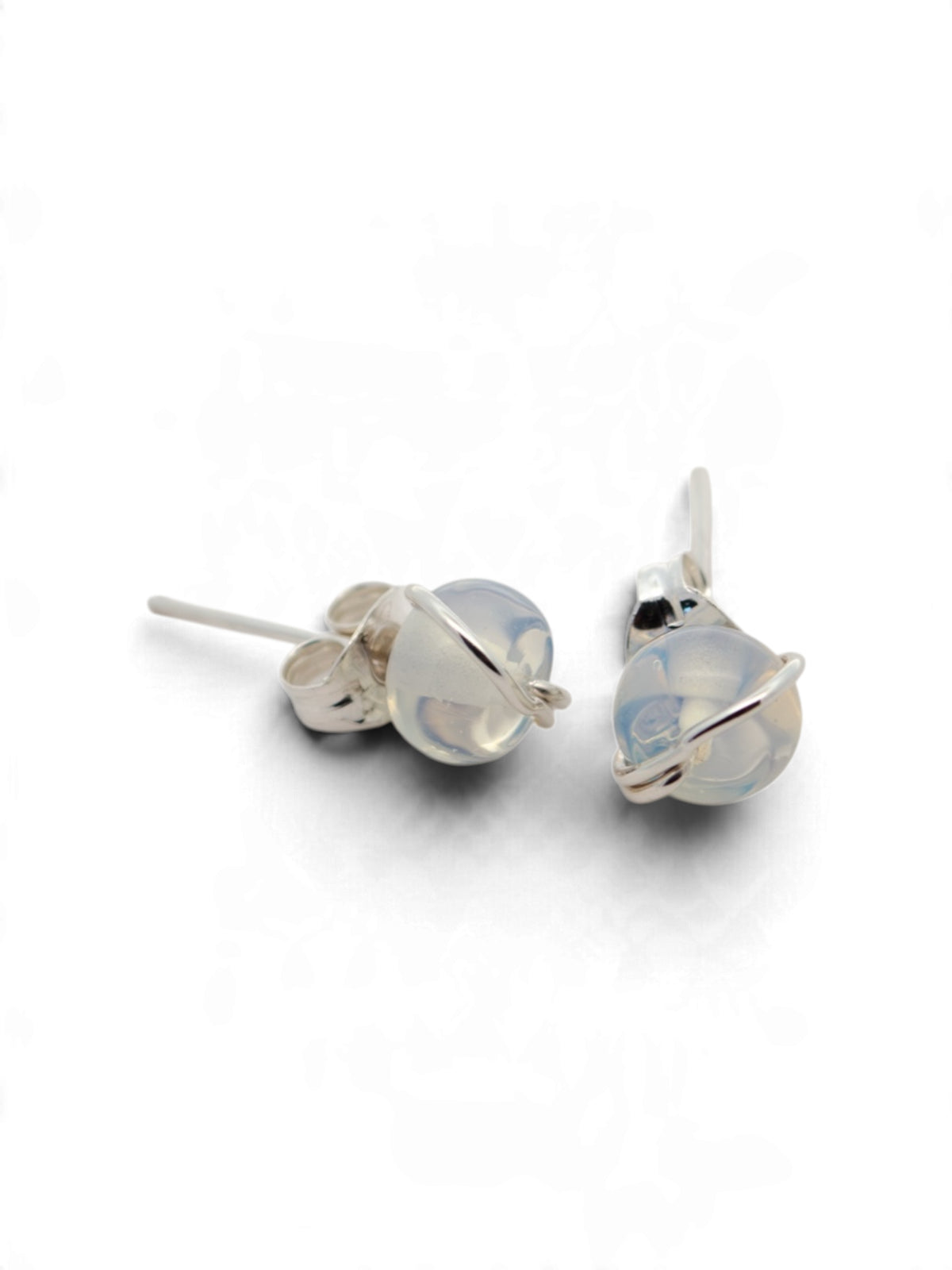 A pair of silver stud earrings with round, milky white cabochon gemstones, shown on a clean white background.