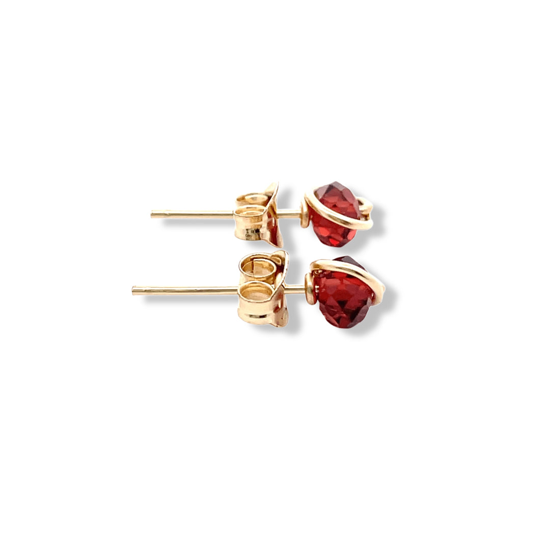 Gold earrings with red gemstones on a white background