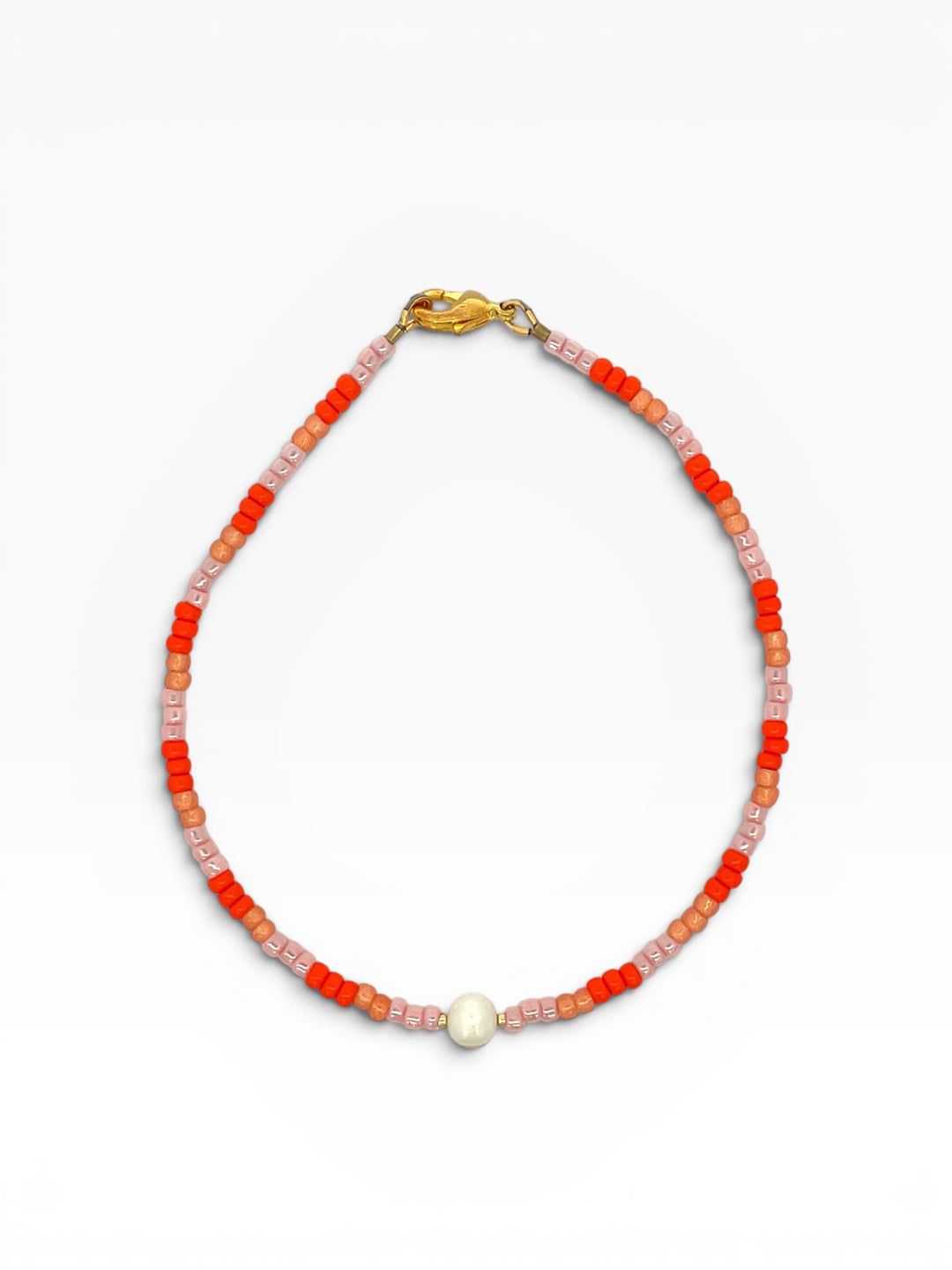 Anklet with orange and pink beads and a pearl on a white background